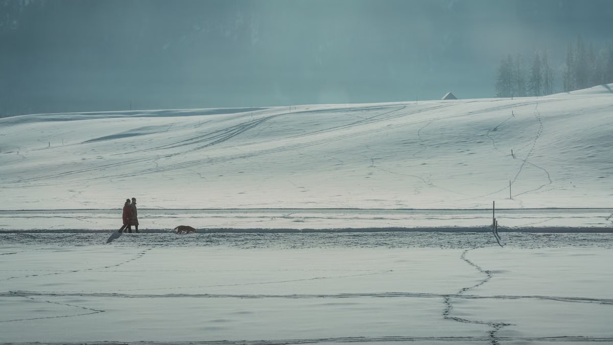 A tranquil winter landscape with a couple walking through snowy fields in Schladming, Austria.